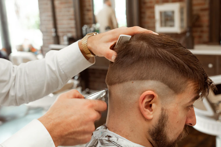 Barbero realizando un corte de cabello a un cliente