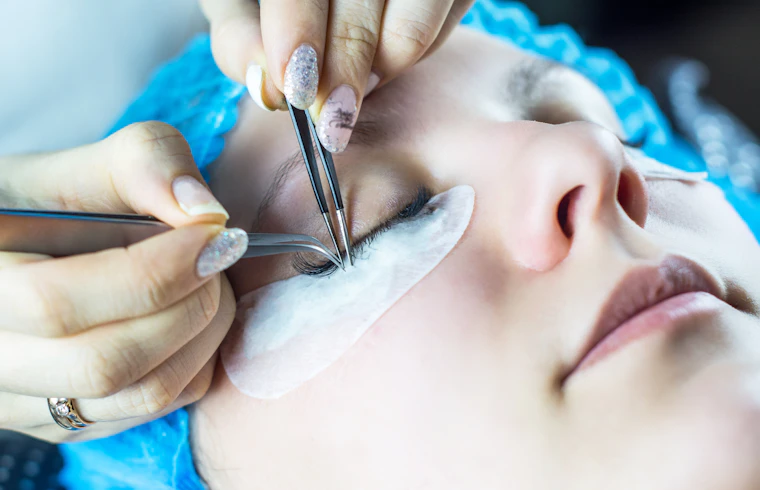 Profesional aplicando extensiones de pestañas a una clienta