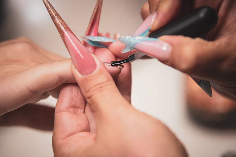 Manicurista pintando las uñas de una clienta